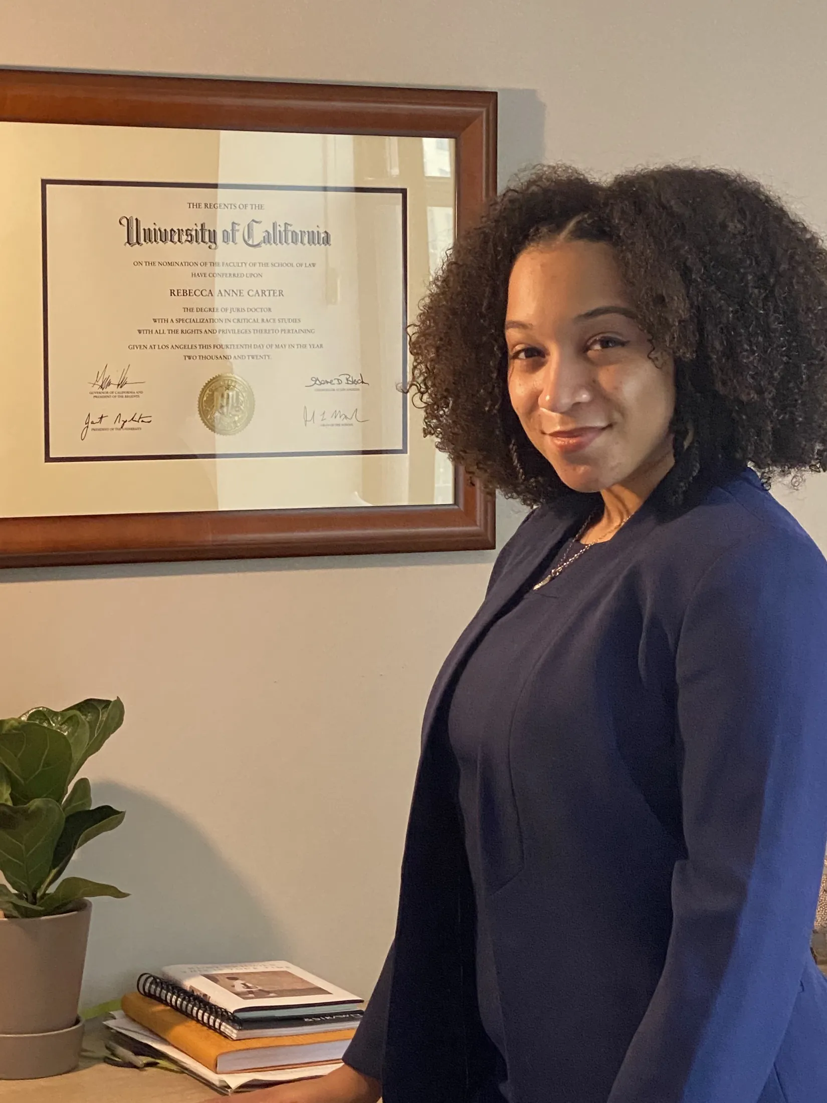 Posing beside a framed law degree